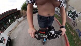 Wind blows girls shirt up showing jugs while rides scooter inside the city